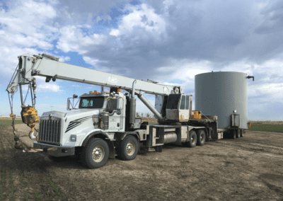 A crane lifting a large white object against a clear sky, showcasing the machinery in action.